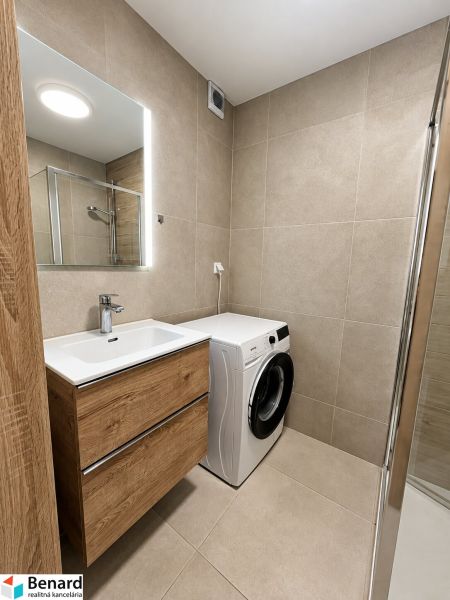 Badezimmer in einer 2-Zimmer-Wohnung mit Waschmaschine und Schrank mit Holzdekor.