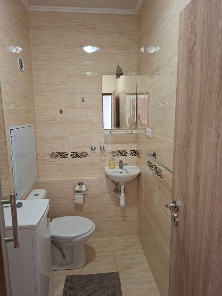 Badezimmer in einem Studio-Apartment mit Fliesen und Sanitäranlagen, kleines Waschbecken und Spiegel.