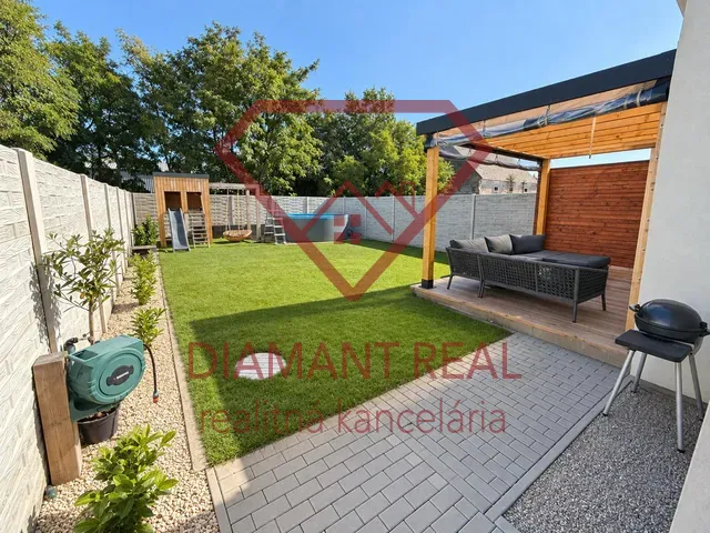 Ein gepflegter Garten eines Einfamilienhauses am Schwarzen Wasser, Schwarzes Wasser, mit Terrasse und Rasen.