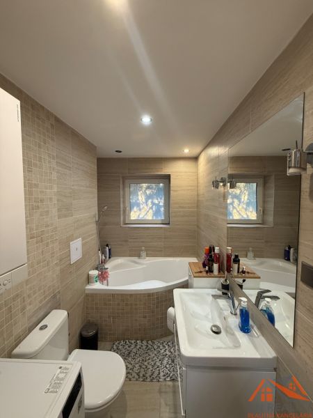 Badezimmer in einer 2-Zimmer-Wohnung mit Badewanne, Waschbecken und Waschmaschine, gefliest.