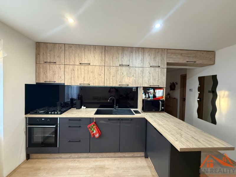 Küche in einer 2-Zimmer-Wohnung mit schwarzen Schränken und einem Boden in Holzoptik.