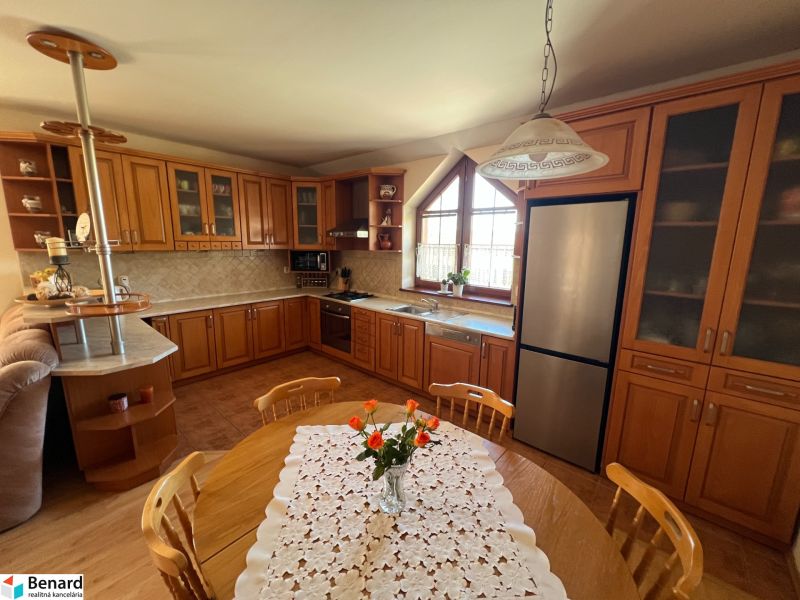 Die Küche eines Einfamilienhauses mit Holzmöbeln, einem Boden mit Holzdekor und einem Esstisch.