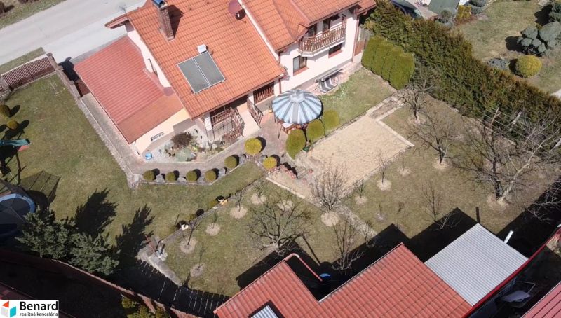 Ein Einfamilienhaus in Stará Ľubovňa mit Garten, Rasen, Pavillon und Solarpaneelen auf dem Dach.