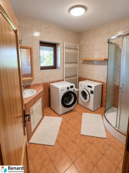 Badezimmer in einem Einfamilienhaus mit Waschmaschine, Trockner und Duschkabine.