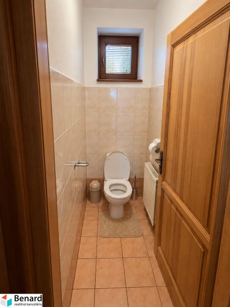 Innenraum eines Familienbadezimmers mit Toilette, Fenster und Fliesen.