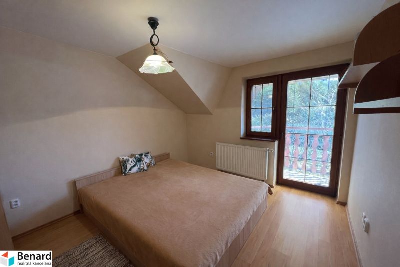 Ein Schlafzimmer in einem Einfamilienhaus mit einem Bett und einem Boden in Holzoptik.