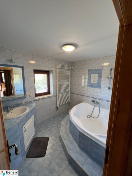 Badezimmer mit Badewanne und Waschbecken in einem Einfamilienhaus, geflieste Wände.
