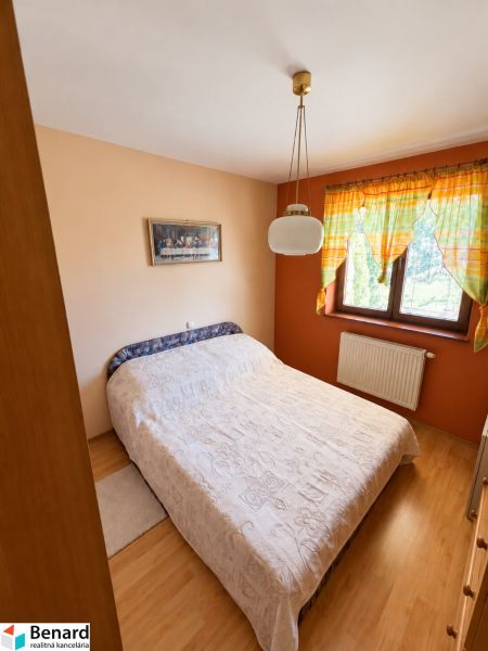 Schlafzimmer in einem Einfamilienhaus mit Bett, Vorhängen und Bodenbelag in Holzoptik.