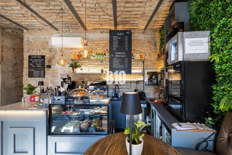 Kaffeehaus mit Backsteinwänden, Theke mit Speisen- und Getränkeangebot, Pflanzen in gastronomischen Räumen.