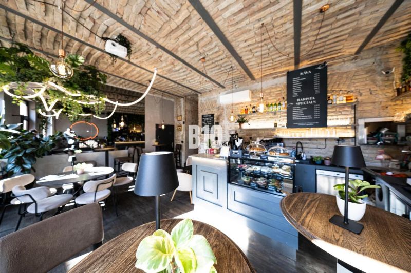 Stilvolle Gastronomiebereiche mit Backsteingewölben, Grünpflanzen und einem Boden in Holzoptik.