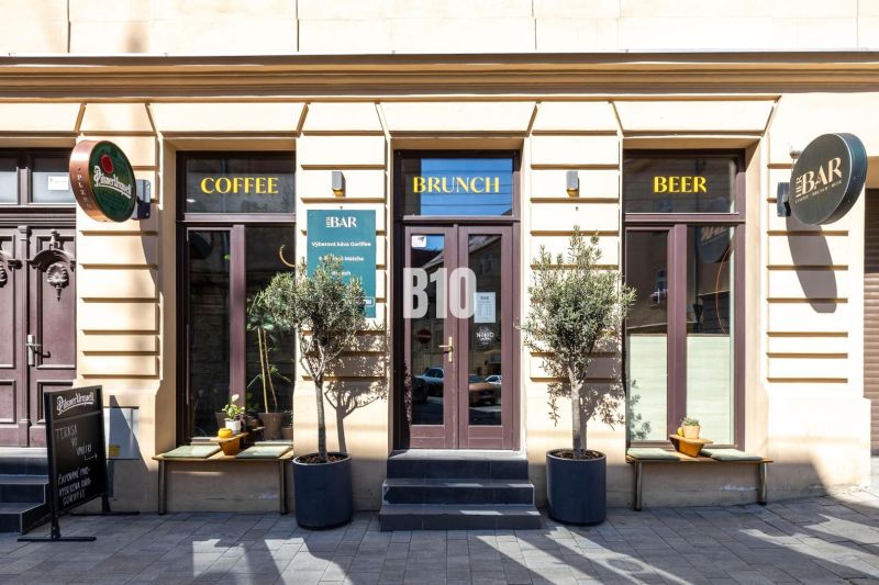 Das Äußere eines Cafés und einer Bar in Bratislava - Altstadt mit drei Eingängen und Schildern.