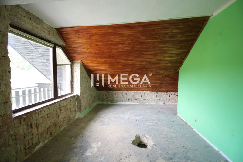 Ein Zimmer in einem Einfamilienhaus mit Holzbalkendecke und freiliegenden Ziegeln.