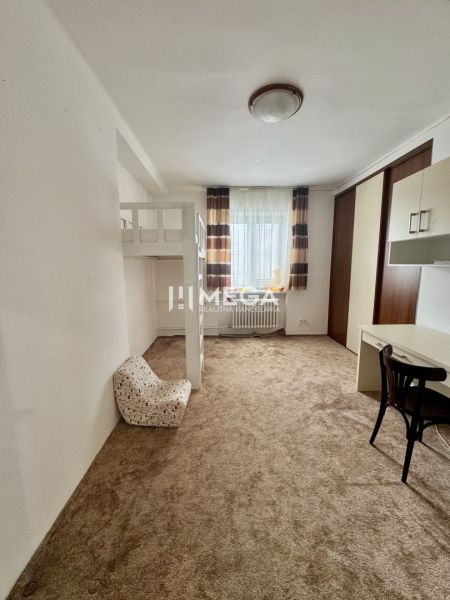 Ein Zimmer mit Teppich, Etagenbett, Schreibtisch und Stuhl in einer 3-Zimmer-Wohnung.