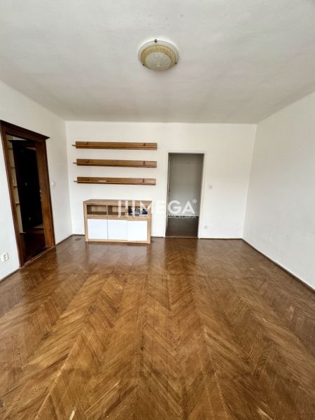 Ein Zimmer in einer 3-Zimmer-Wohnung mit einem Boden in Holzoptik und Regalen an der Wand.