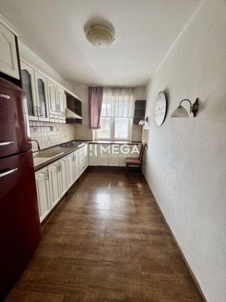 Küche in einer 3-Zimmer-Wohnung mit Holzboden, weißen Möbeln, rotem Kühlschrank.