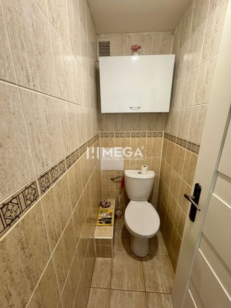 Toilette mit Fliesen und weißen Möbeln in einer 3-Zimmer-Wohnung.