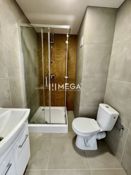 Badezimmer in einer Einzimmerwohnung mit Duschkabine und Keramikfliesen.