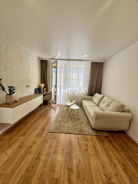 Wohnzimmer in einer Einzimmerwohnung mit einem Sofa und einem Boden in Holzoptik.