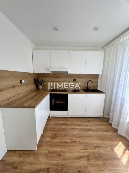Küche mit weißen Schränken, Holzelementen und Boden in einem Einzimmerapartment.