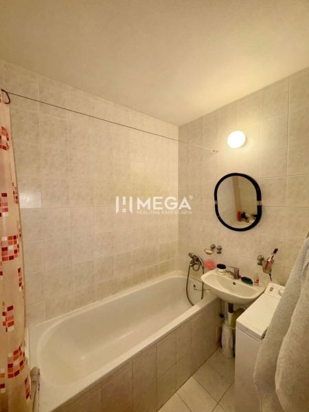 Badezimmer mit Badewanne und Waschbecken in einer 3-Zimmer-Wohnung, helle Fliesen.