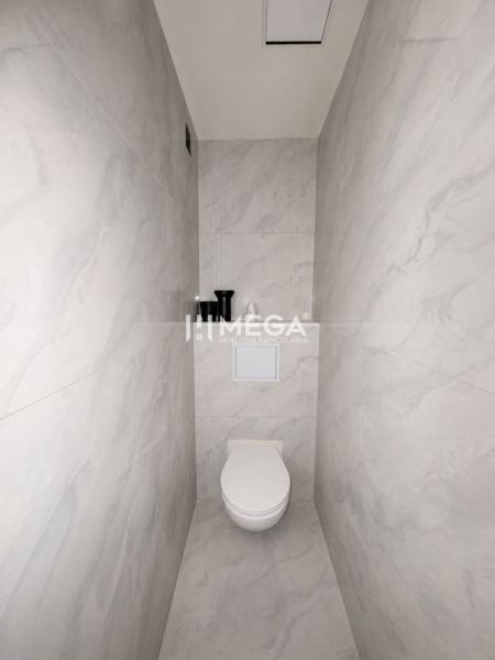 Toilette mit minimalistischem Design und hellen Keramikfliesen in einer 3-Zimmer-Wohnung.