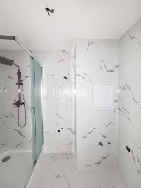 Badezimmer mit Duschkabine in einer 2-Zimmer-Wohnung mit Marmorfliesen.