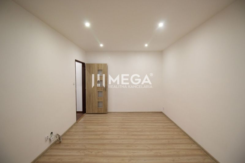 Ein leerer Raum in einer Ferienwohnung mit Holzboden und heller Wandfarbe.