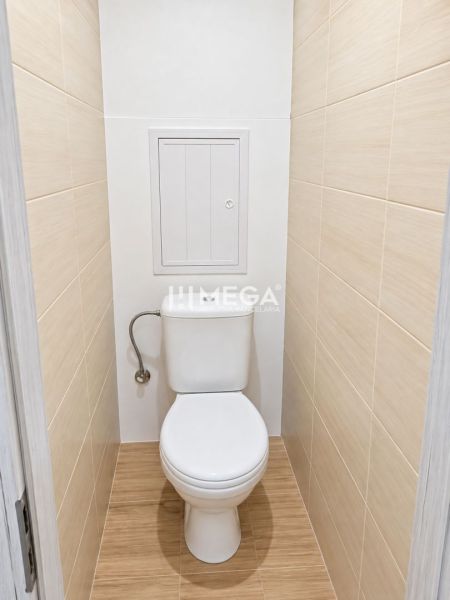 Badezimmer in einer 2-Zimmer-Wohnung mit Fliesen und Boden in Holzoptik.