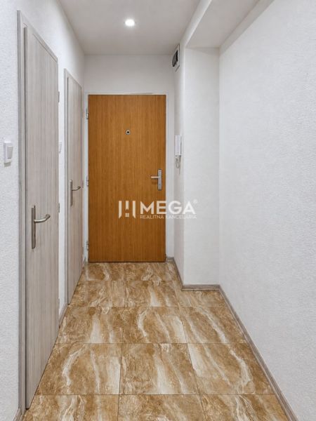Der Flur einer 2-Zimmer-Wohnung mit einem Boden in Marmoroptik und weißen Wänden.