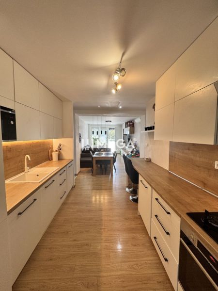 Küche in einer 3-Zimmer-Wohnung mit Holzboden und weißen Schränken.