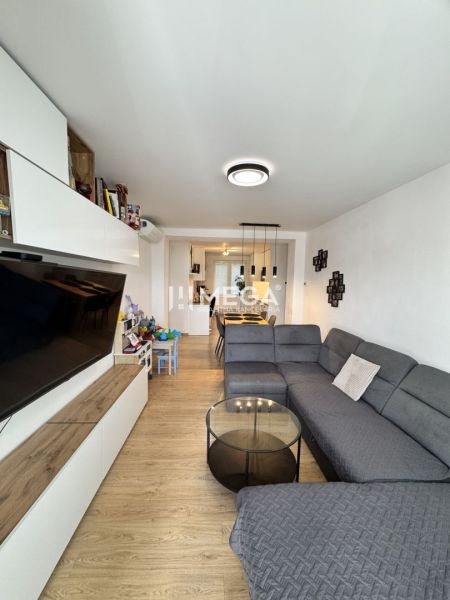 Wohnzimmer in einer 3-Zimmer-Wohnung mit Holzboden und grauem Sofa.