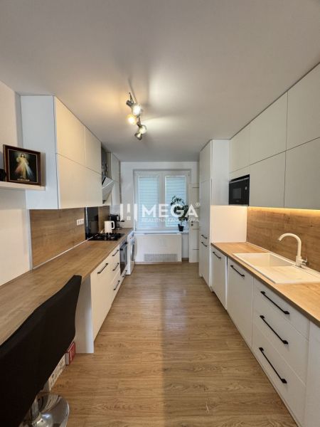 Küche in einer 3-Zimmer-Wohnung mit Holzboden und weißen Schränken.