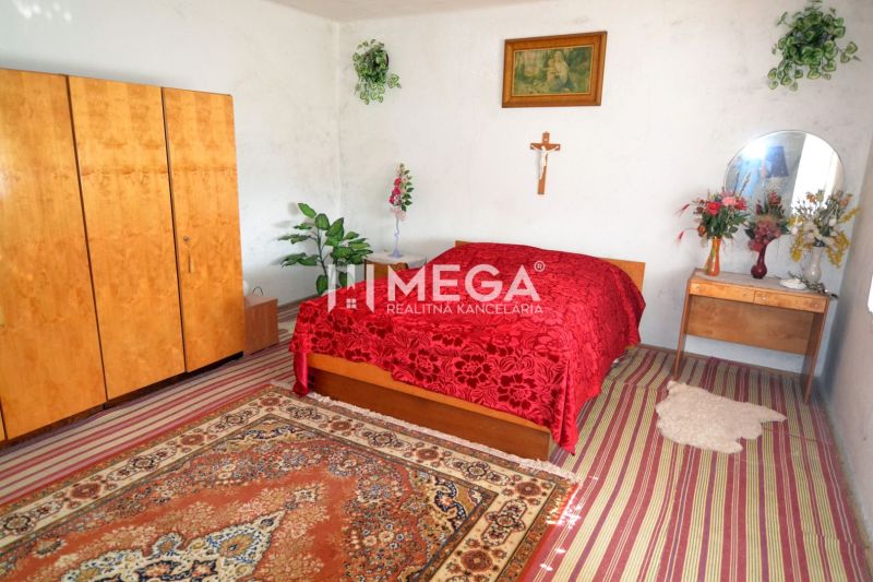Ein Schlafzimmer in einem Einfamilienhaus mit einer roten Decke, Holzmöbeln und dekorativen Blumen.
