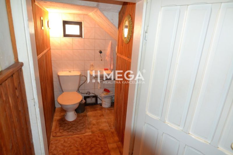 Toilette mit Fliesen und kleinem Fenster in einem Einfamilienhaus.