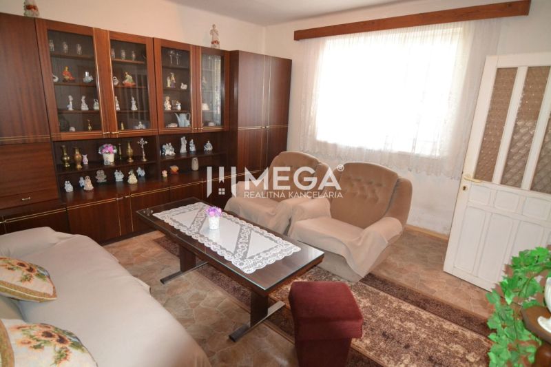 Wohnzimmer in einem Einfamilienhaus mit Vitrine, Sesseln und Tisch mit Spitze.