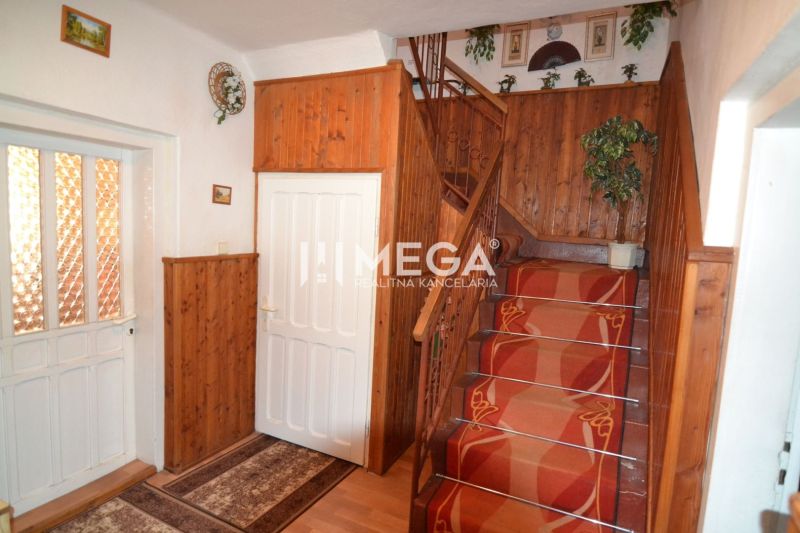 Eine Treppe in einem Einfamilienhaus mit Holzverkleidungen und rotem Teppich.