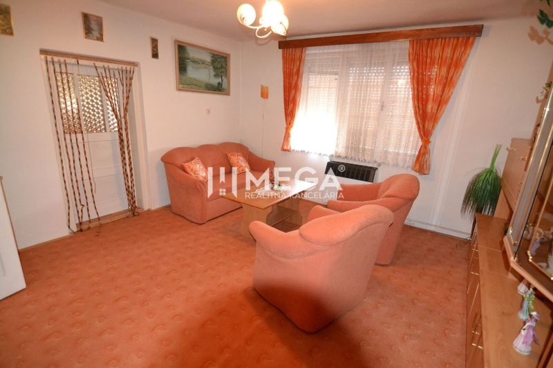 Wohnzimmer in einem Einfamilienhaus mit orangefarbenen Möbeln und Teppich, Vorhänge an den Fenstern.