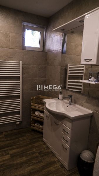 Badezimmer mit Waschbecken, Schrank, Handtuchheizkörper und Boden mit Holzdekor.