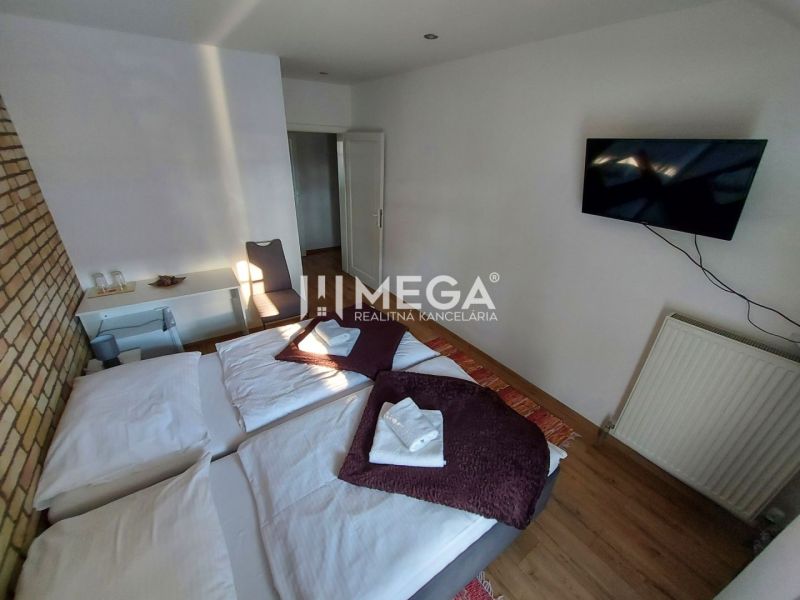 Ein Hotelzimmer mit einer Backsteinwand, zwei Betten, einem Fernseher und einem Boden mit Holzdekor.
