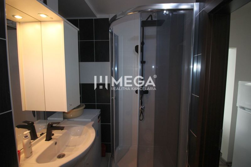 Badezimmer in der Ferienwohnung mit Waschbecken, Duschkabine und beleuchtetem Spiegel.