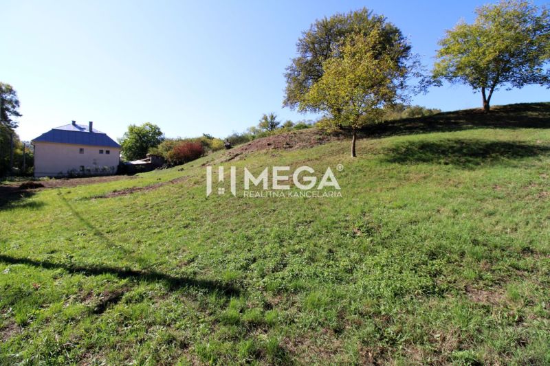 Grünes, hügeliges Grundstück für Wohnzwecke in Vyšné Ladičkovce mit Blick auf ein Haus und Bäume.