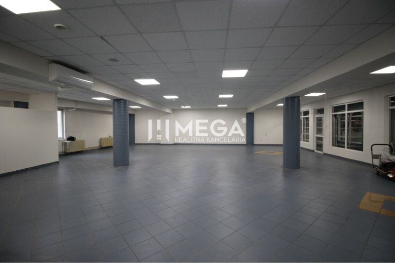 Geräumige Geschäftsräume mit dunklen Fliesen und abgehängter Decke, geeignet für Unternehmen.