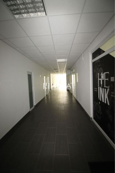 Ein langer Flur im Büro mit dunklem Boden und weißer Decke.