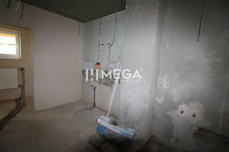 Unvollendetes Interieur in einem Einfamilienhaus mit Betonboden und Anschluss für einen Heizkörper.