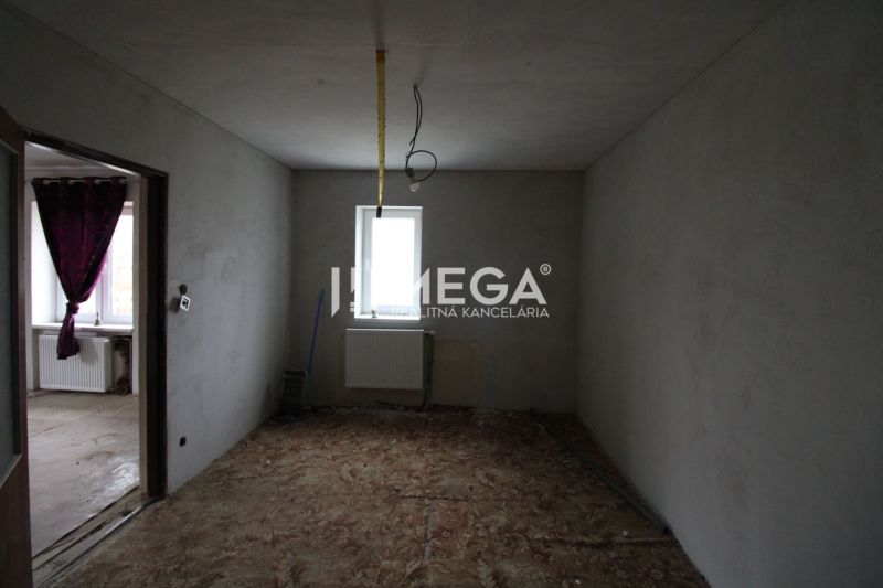 Eckzimmer in einem Einfamilienhaus mit Betonboden und nackten Wänden.