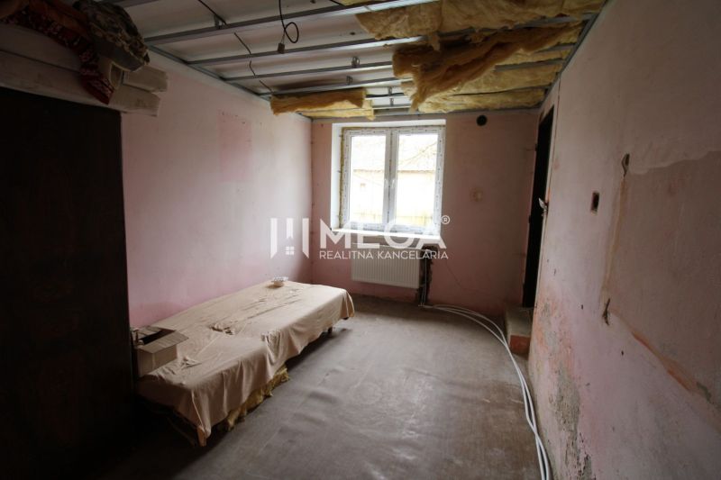 Unmöbliertes Interieur eines Einfamilienhauses mit Bett und freiliegender Decke.