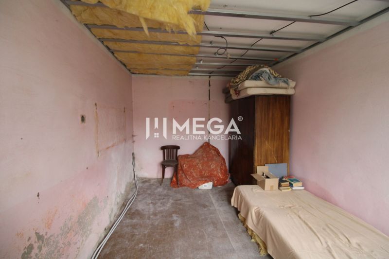 Ein Zimmer in einem Einfamilienhaus mit rosa Wänden, einem Bett und einem Schrank.