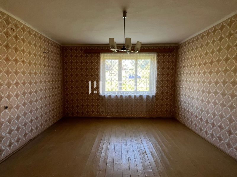 Ein Zimmer mit Tapeten und einem Boden in Holzoptik in einem Einfamilienhaus.