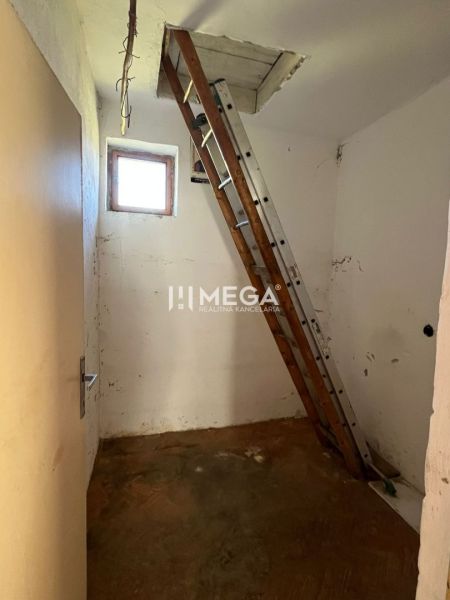 Eine Leiter führt auf den Dachboden in einem Einfamilienhaus mit einem Boden in Holzoptik.