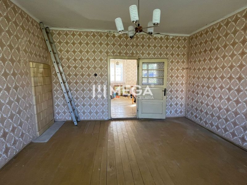 Ein Zimmer in einem Einfamilienhaus mit einem Boden in Holzoptik und gemusterten Tapeten.
